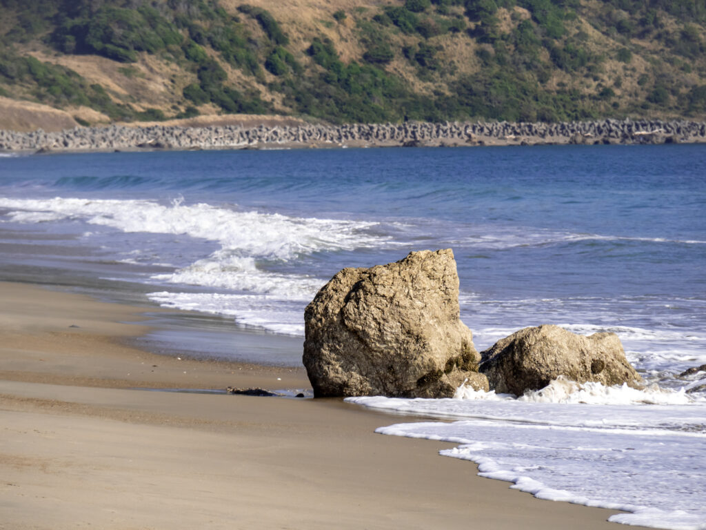 恋路ヶ浜の波打ち際の岩と砂浜の風景